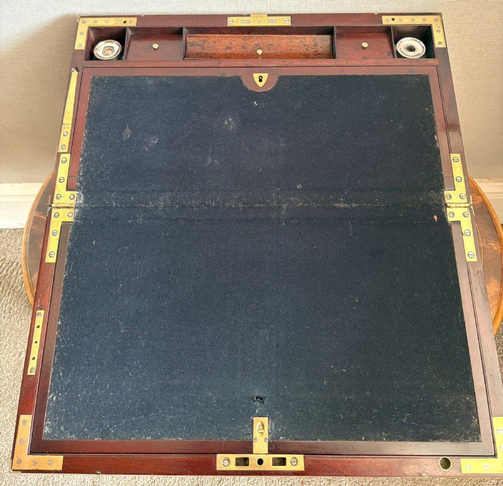 A rectangular mahogany writing slope box featuring flush brass corner brackets, brass strapping, and a central brass inlay. View IV