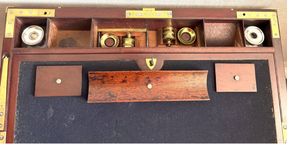 A rectangular mahogany writing slope box featuring flush brass corner brackets, brass strapping, and a central brass inlay. View V