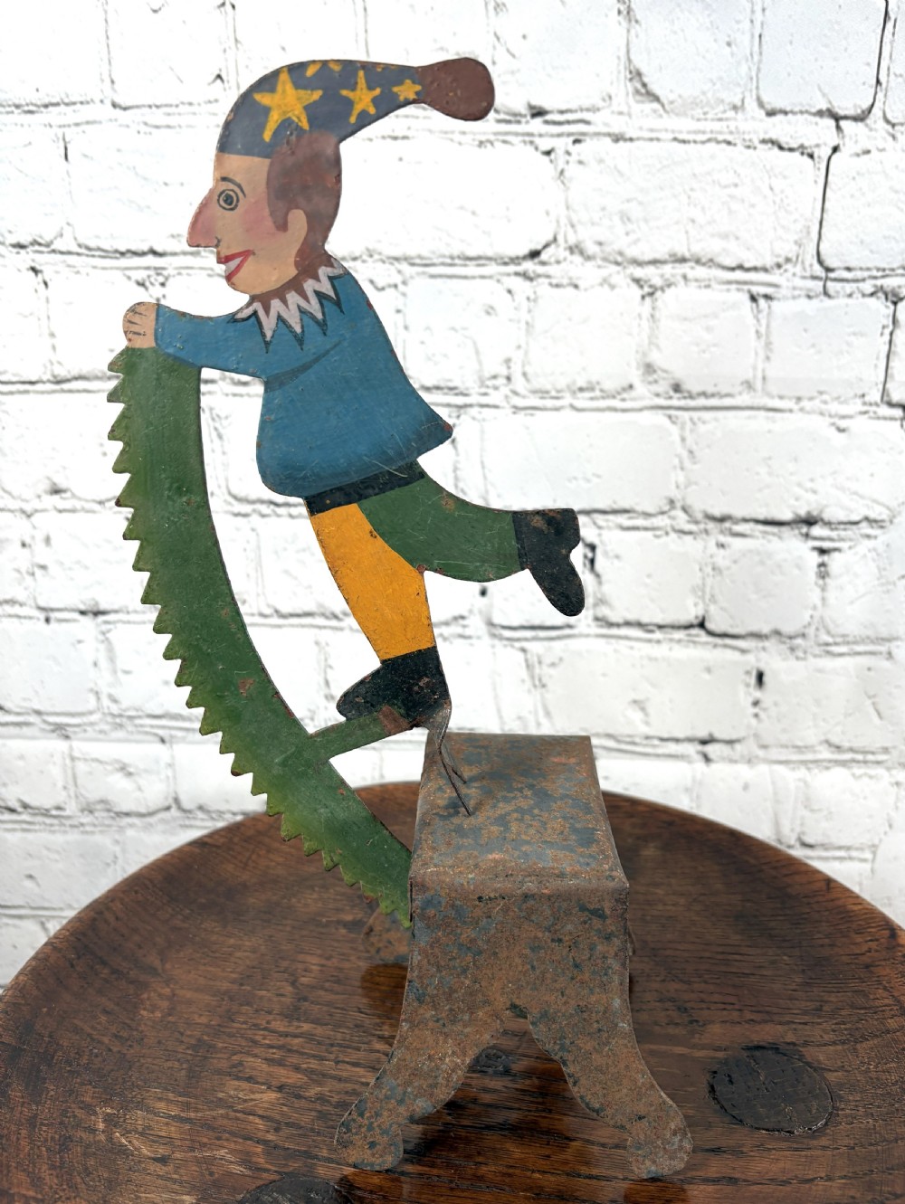 A painted sheet-metal kinetic balance toy featuring a jester figure in a starred hat balancing on a rusted iron pedestal.
