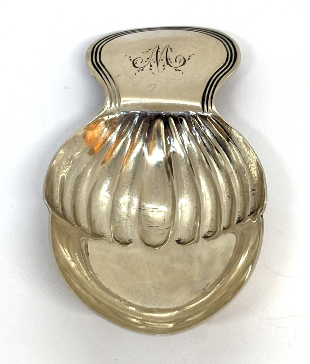 A Georgian sterling silver caddy spoon featuring an acorn-form fluted bowl and stamped British hallmarks on the short handle. View II