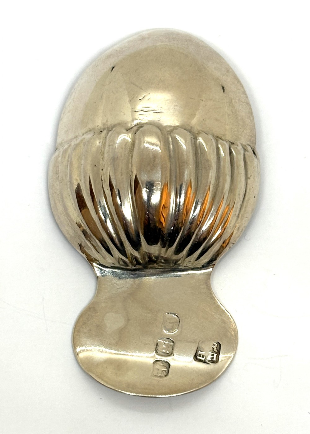 A Georgian sterling silver caddy spoon featuring an acorn-form fluted bowl and stamped British hallmarks on the short handle. View III