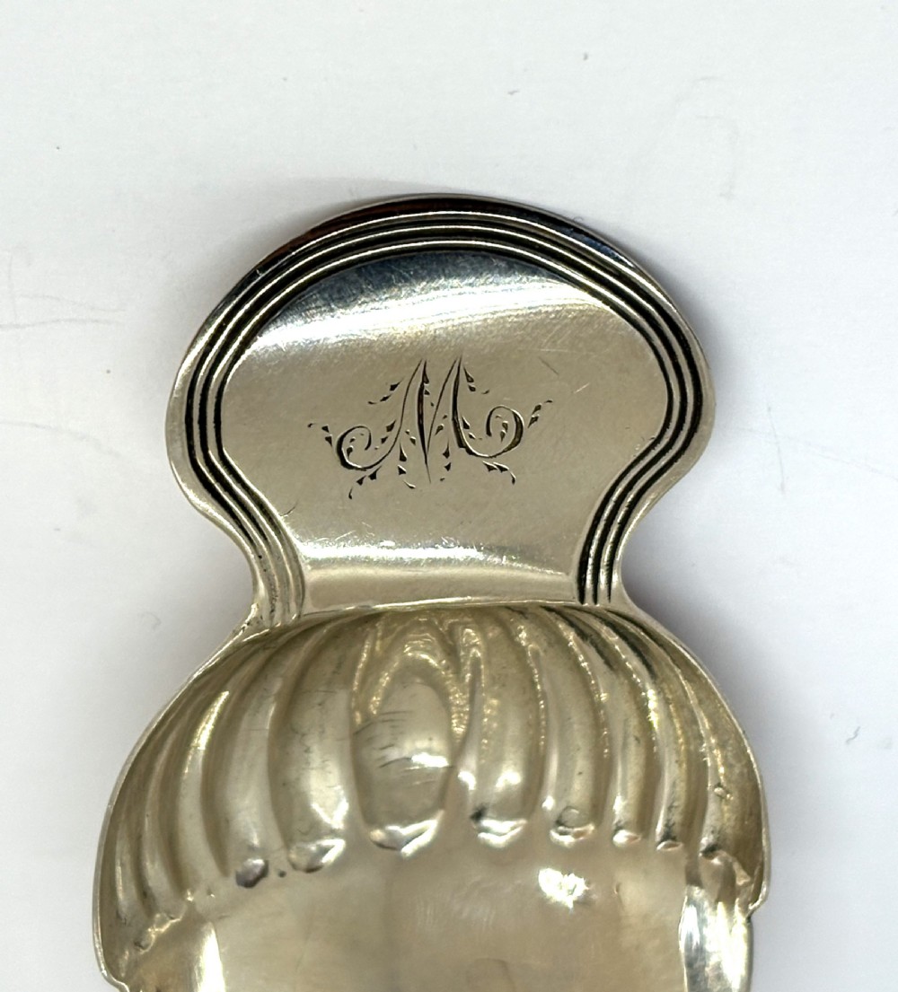 A Georgian sterling silver caddy spoon featuring an acorn-form fluted bowl and stamped British hallmarks on the short handle. View IV