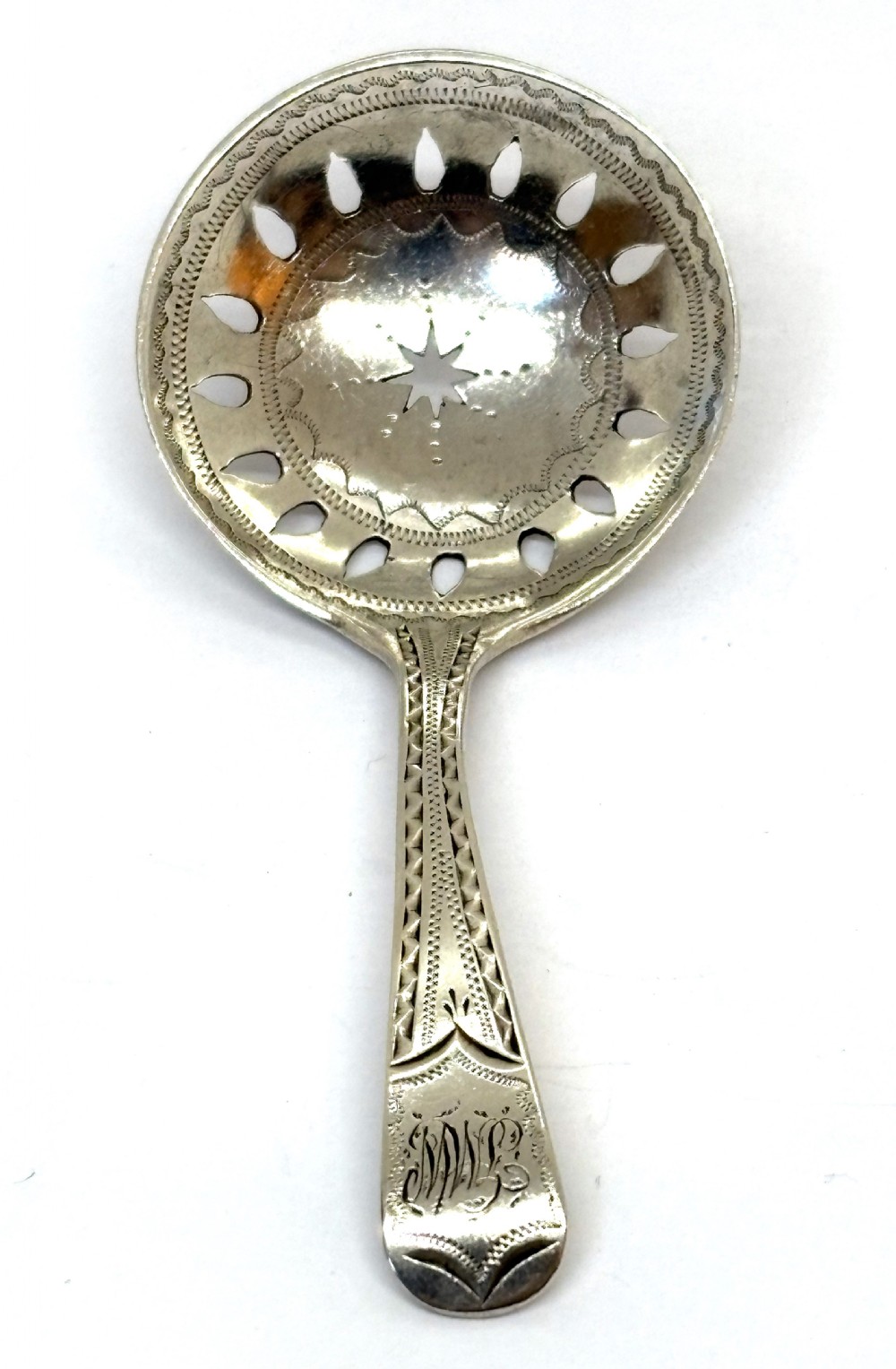 A sterling silver Georgian caddy spoon featuring a circular pierced bowl with bright-cut engraving and a monogrammed handle terminal.
