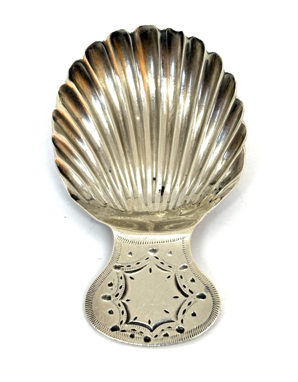 A Georgian sterling silver caddy spoon featuring a fluted shell bowl and an engraved handle.