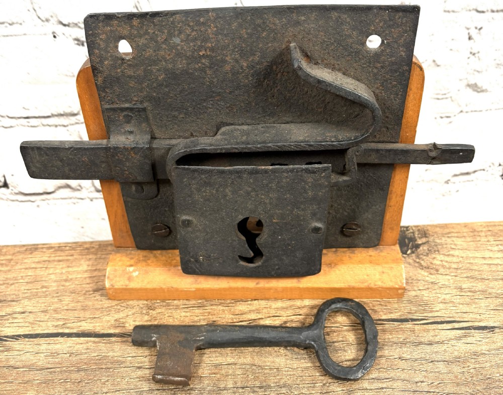 A 16th-century hand-forged wrought iron rim lock mechanism with a large iron key inserted into the lock plate. View II