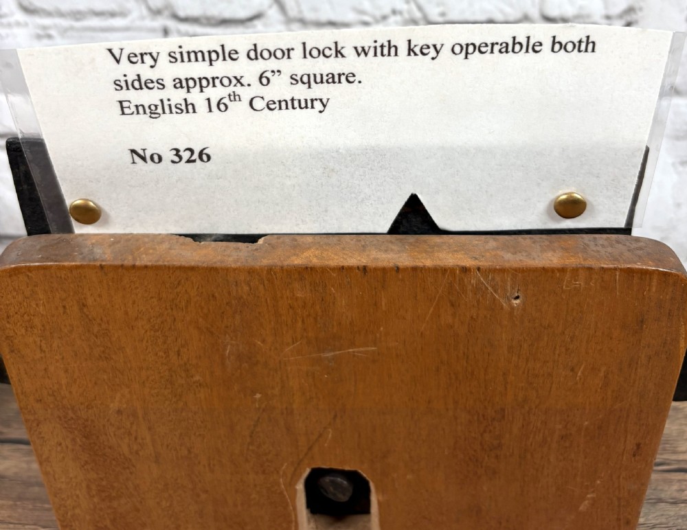 A 16th-century hand-forged wrought iron rim lock mechanism with a large iron key inserted into the lock plate. View V