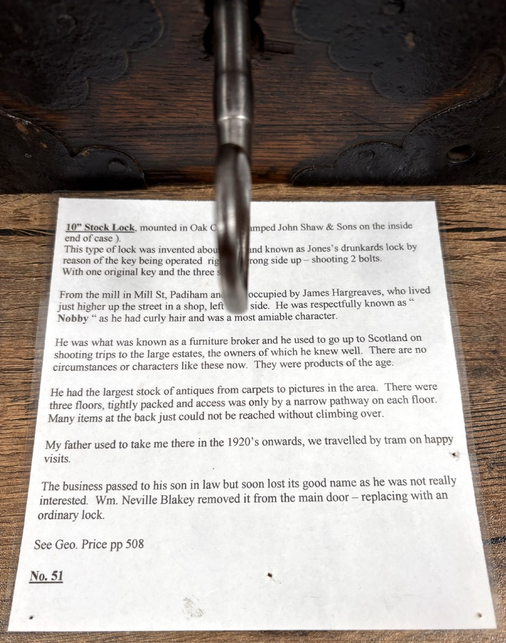 A 19th-century rectangular oak cased stock lock with decorative black iron corner plates, a central keyhole, and an inserted iron key. View VII