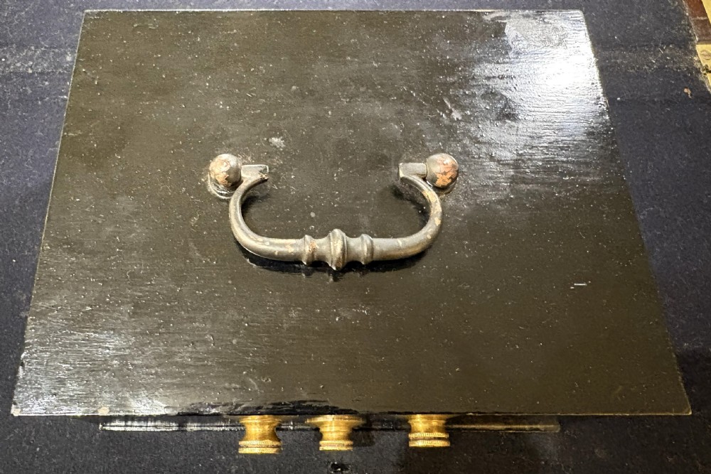 A rectangular black iron safe box featuring a top metal handle and three brass combination dials on the front. View II