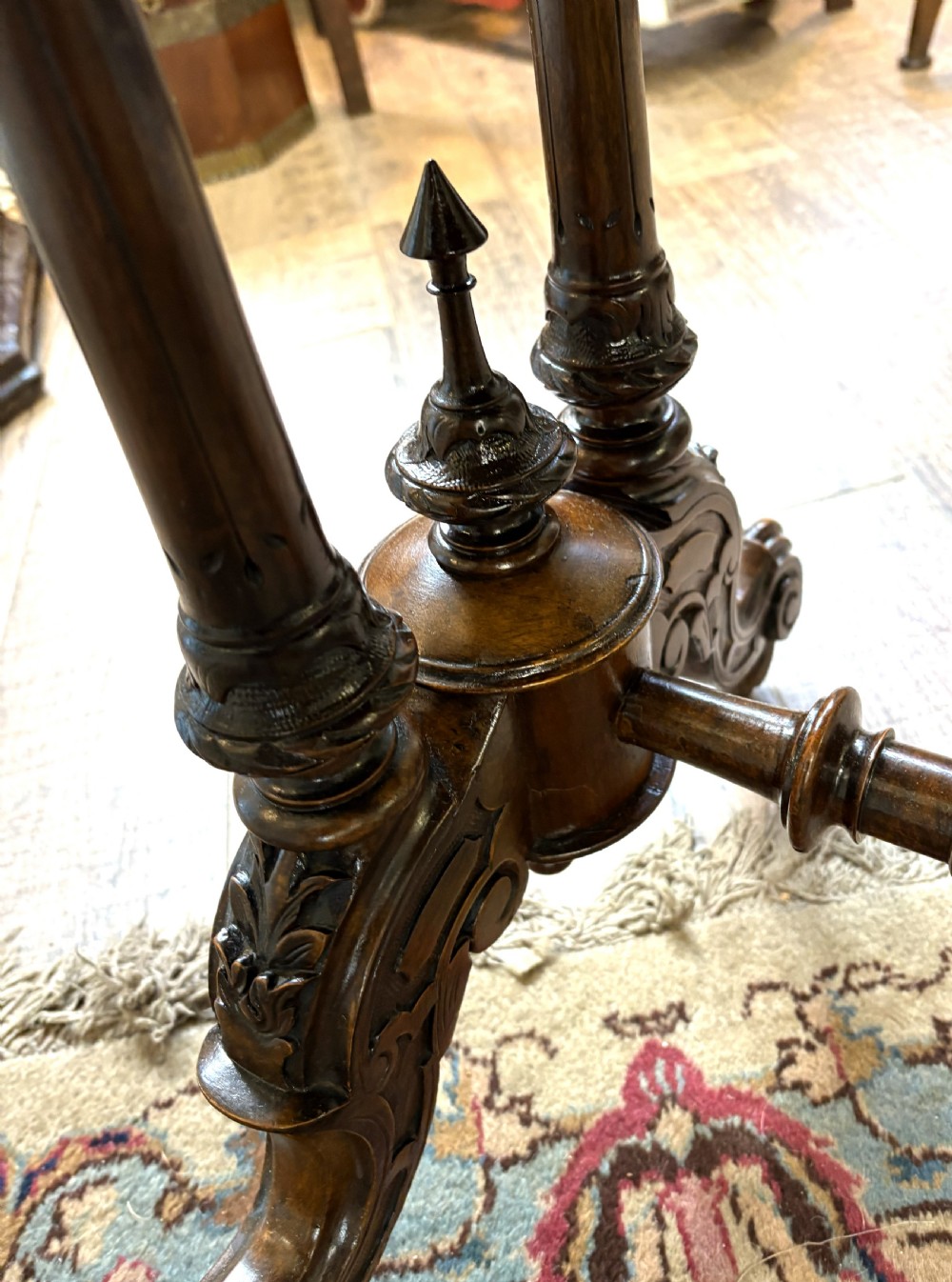 An oval Victorian burr walnut stretcher table featuring marquetry inlays, turned twin-column supports, a central stretcher rail, and carved legs with castors. View IX