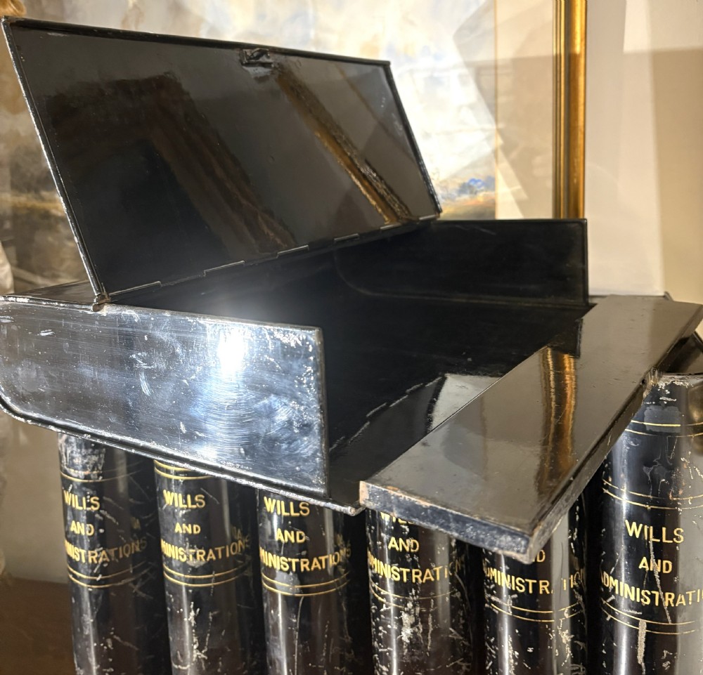 A set of seven black painted metal cylindrical toleware tins featuring gold-lettered spines reading Wills and Administrations alongside early twentieth-century dates. View III