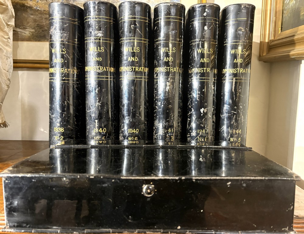 A set of seven black painted metal cylindrical toleware tins featuring gold-lettered spines reading Wills and Administrations alongside early twentieth-century dates. View IV