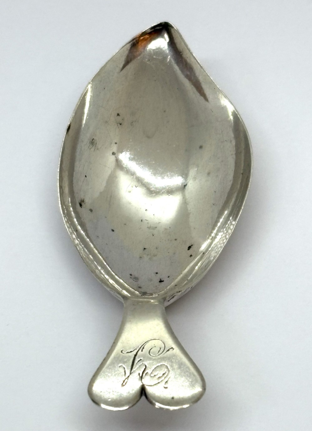 An antique Georgian sterling silver tea caddy spoon featuring a tear-shaped bowl and a flared handle with engraved monogram lettering. View II