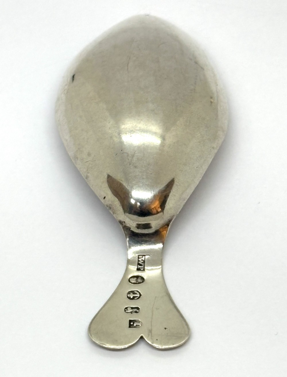 An antique Georgian sterling silver tea caddy spoon featuring a tear-shaped bowl and a flared handle with engraved monogram lettering. View V