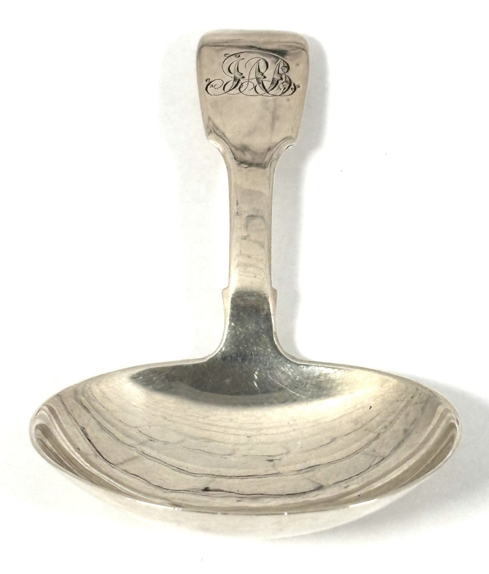 A Georgian sterling silver tea caddy spoon featuring a broad oval bowl and a flat handle with an engraved monogram. View II
