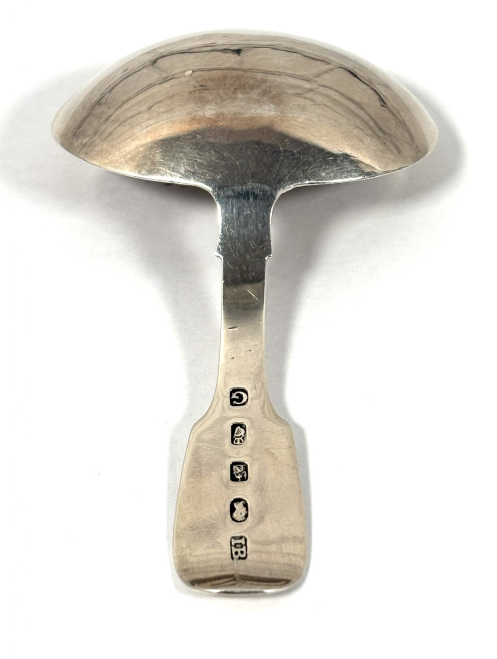 A Georgian sterling silver tea caddy spoon featuring a broad oval bowl and a flat handle with an engraved monogram. View III