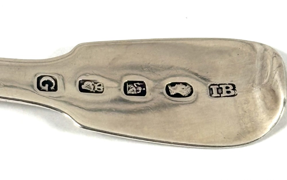 A Georgian sterling silver tea caddy spoon featuring a broad oval bowl and a flat handle with an engraved monogram. View V