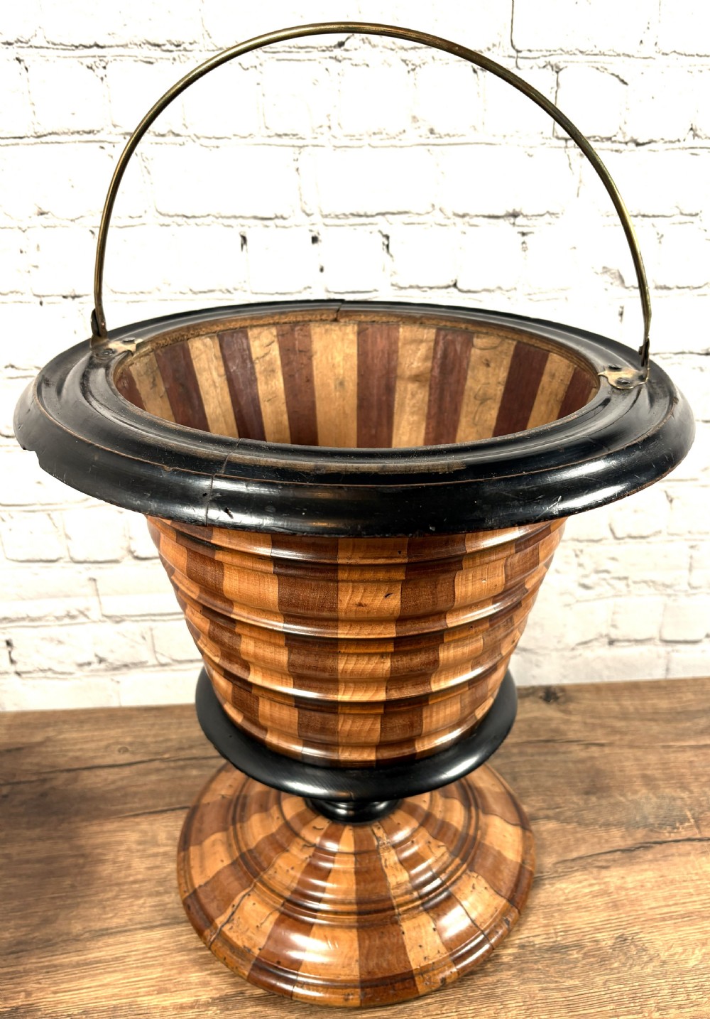 An antique early 19th-century Dutch teestoof featuring staved wood with alternating light and dark stripes, an ebonised rim, pedestal base, and a brass swing handle.