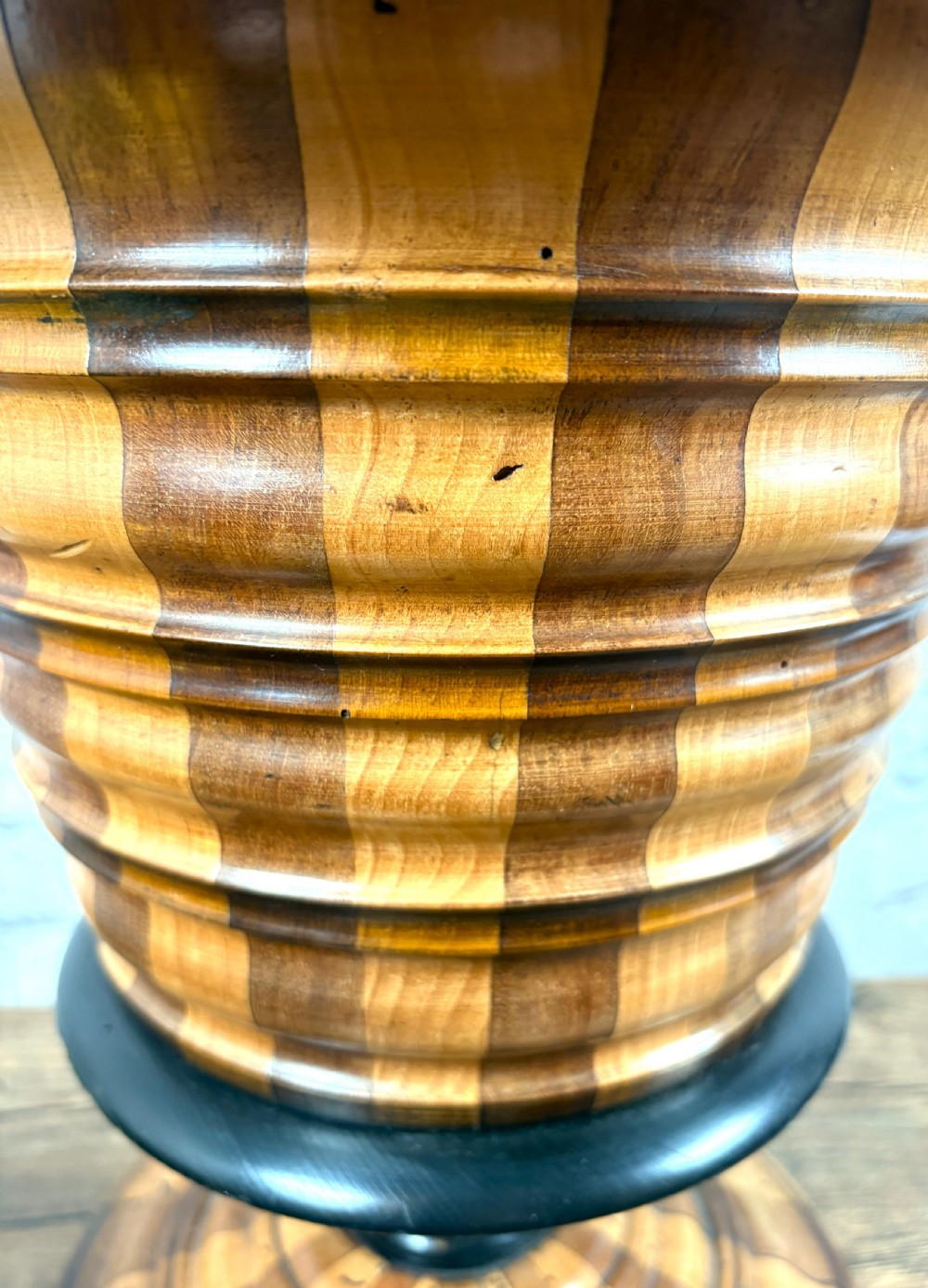 An antique early 19th-century Dutch teestoof featuring staved wood with alternating light and dark stripes, an ebonised rim, pedestal base, and a brass swing handle. View VI