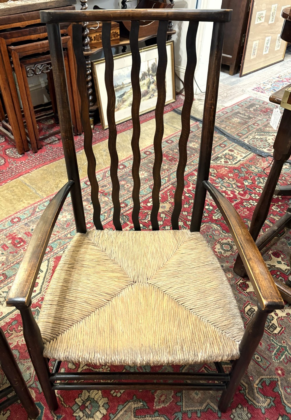A pair of antique Arts and Crafts high-back dark wood armchairs featuring wavy back slats and woven natural rush seats. View II