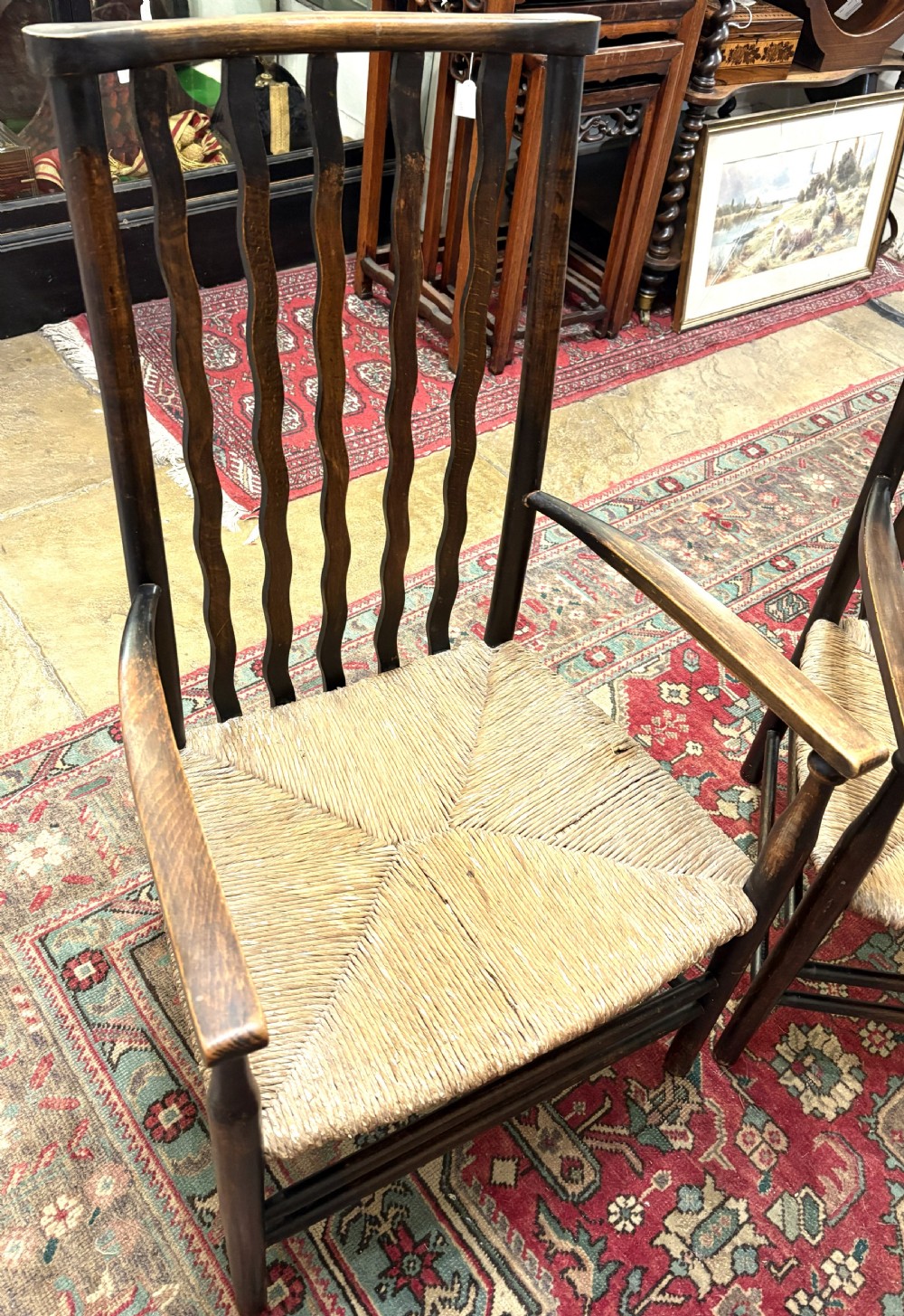 A pair of antique Arts and Crafts high-back dark wood armchairs featuring wavy back slats and woven natural rush seats. View III