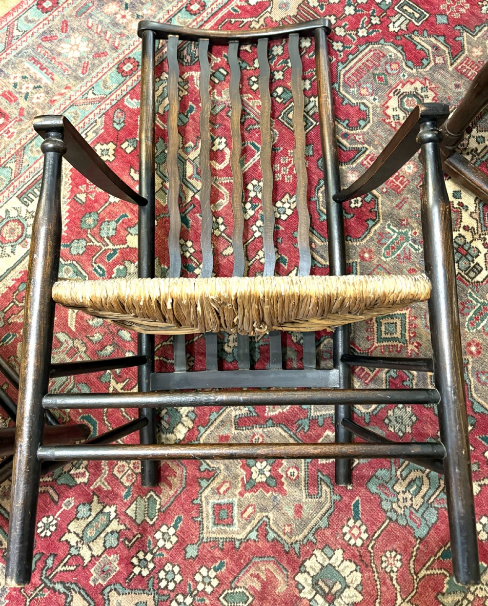 A pair of antique Arts and Crafts high-back dark wood armchairs featuring wavy back slats and woven natural rush seats. View V