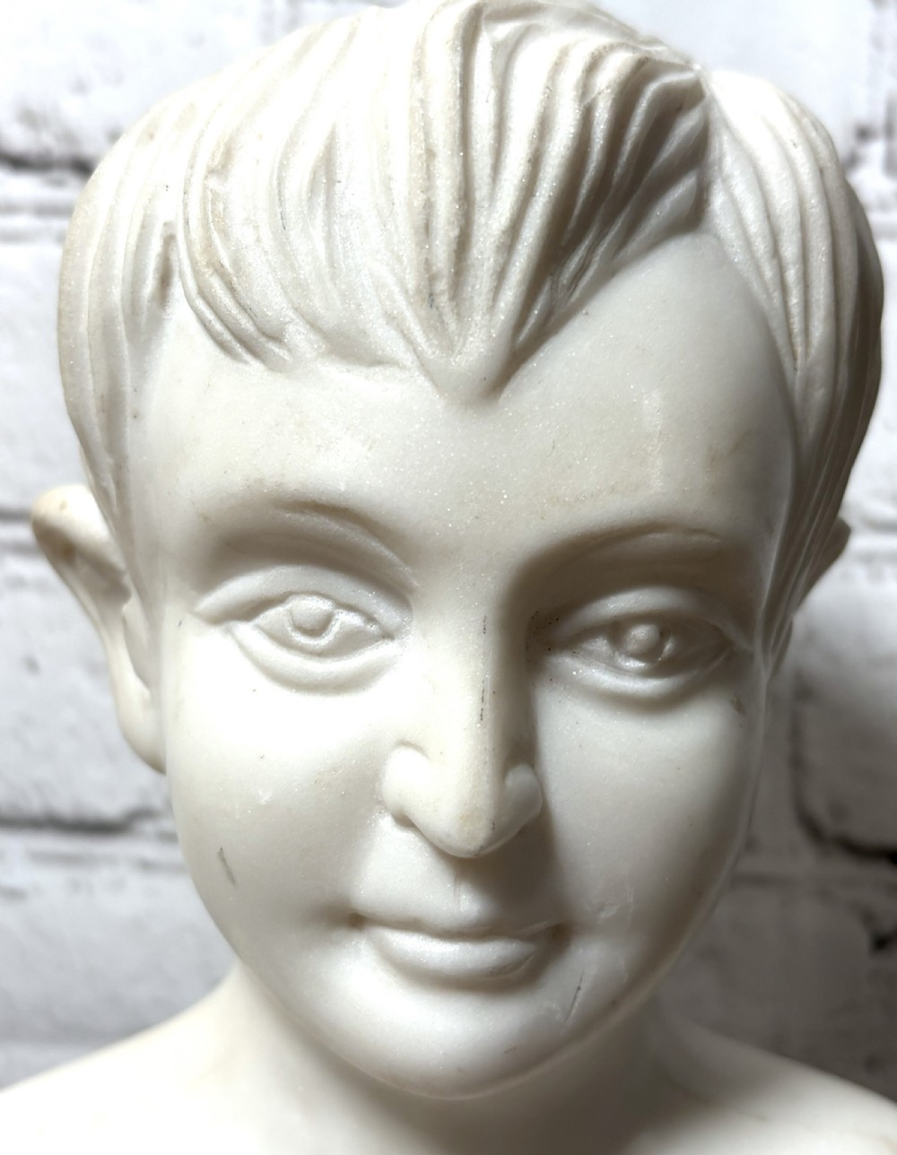 Carved white marble portrait bust depicting a young boy, raised on a dark green turned marble socle base. View II