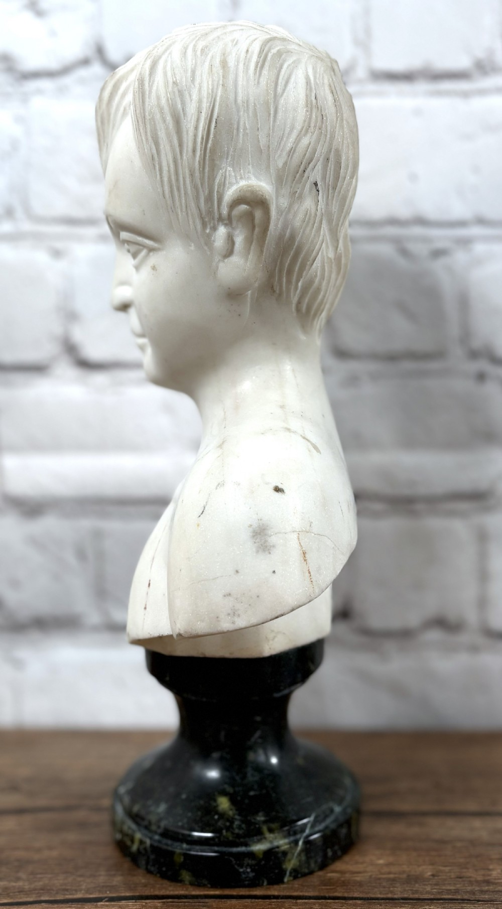 Carved white marble portrait bust depicting a young boy, raised on a dark green turned marble socle base. View III