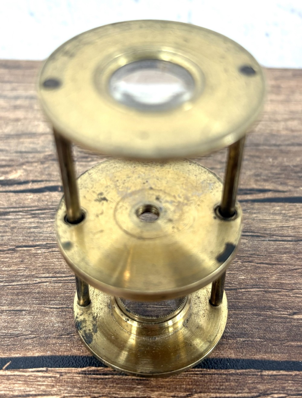A Georgian brass travelling botanical microscope featuring three circular stages alongside its original red textured leather cylindrical case. View II