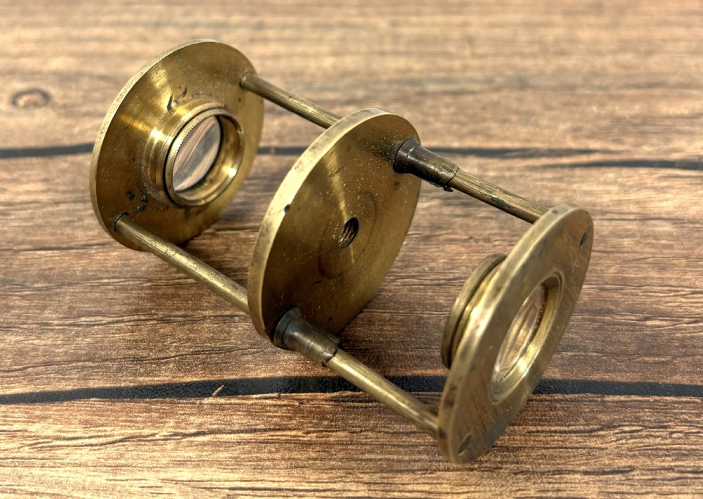 A Georgian brass travelling botanical microscope featuring three circular stages alongside its original red textured leather cylindrical case. View III