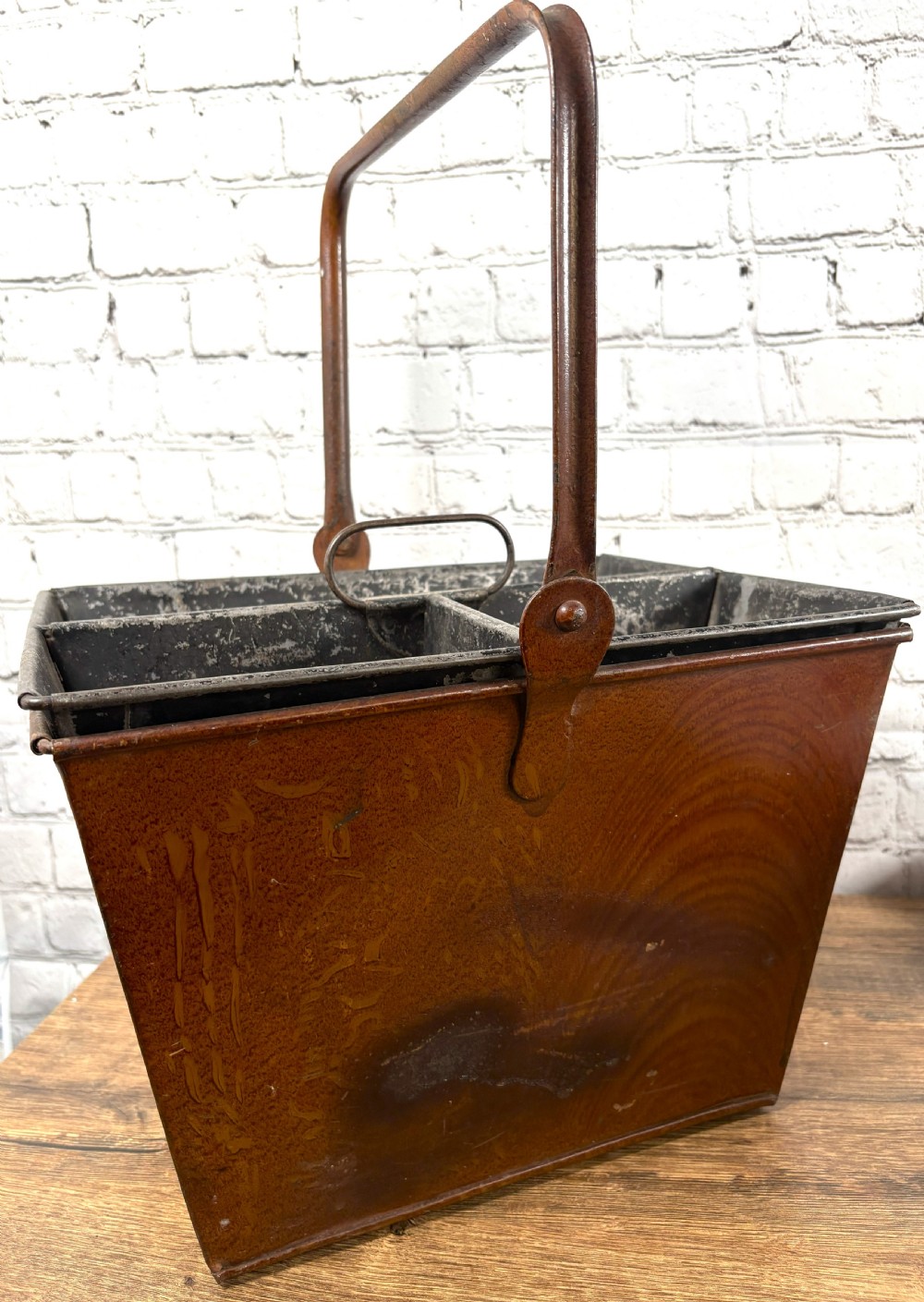 A Victorian painted sheet iron housemaid caddy featuring a faux-wood grain finish, internal compartments, and a tall metal carrying handle.
