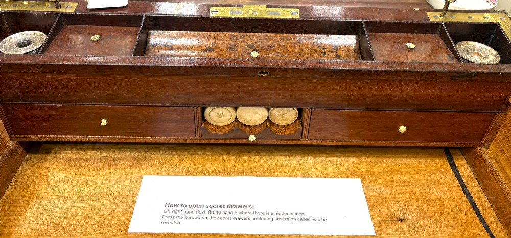 A rectangular mahogany writing slope box featuring flush brass corner brackets, brass strapping, and a central brass inlay. View VIII