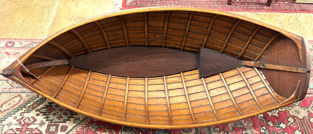 A nineteenth-century clinker-built wooden boat hull cradle with metal rivets and warm timber tones. View IV