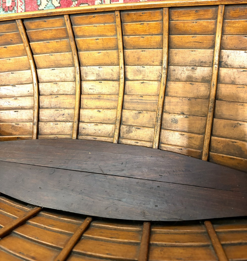 A nineteenth-century clinker-built wooden boat hull cradle with metal rivets and warm timber tones. View VI