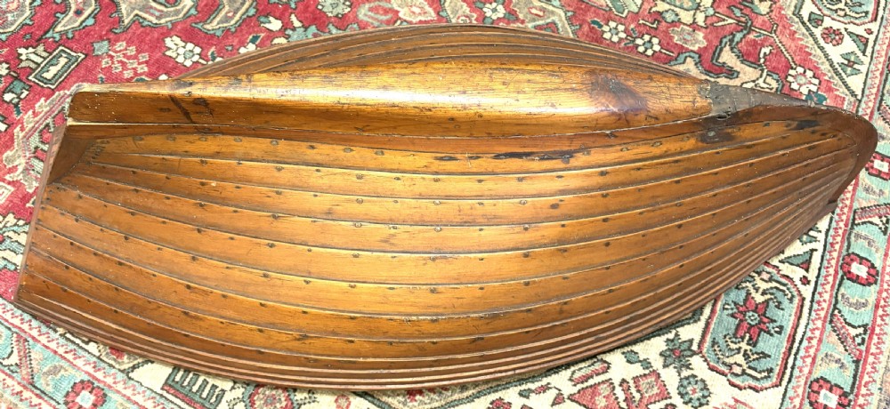 A nineteenth-century clinker-built wooden boat hull cradle with metal rivets and warm timber tones. View VIII