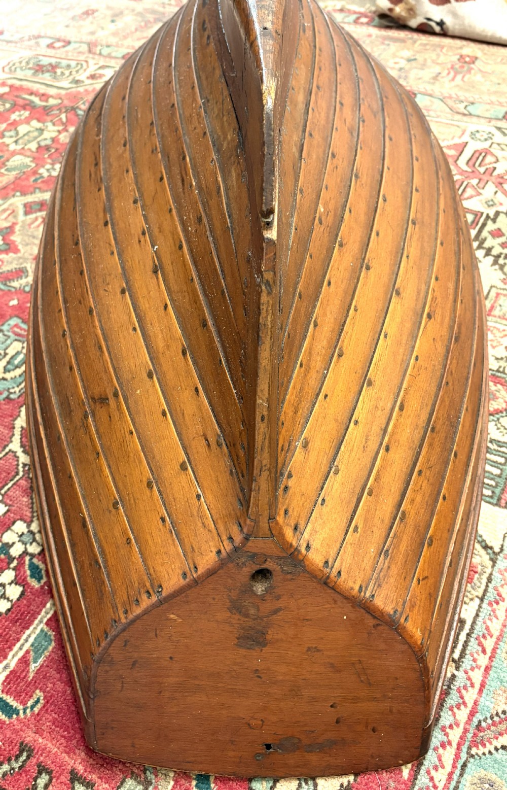 A nineteenth-century clinker-built wooden boat hull cradle with metal rivets and warm timber tones. View IX