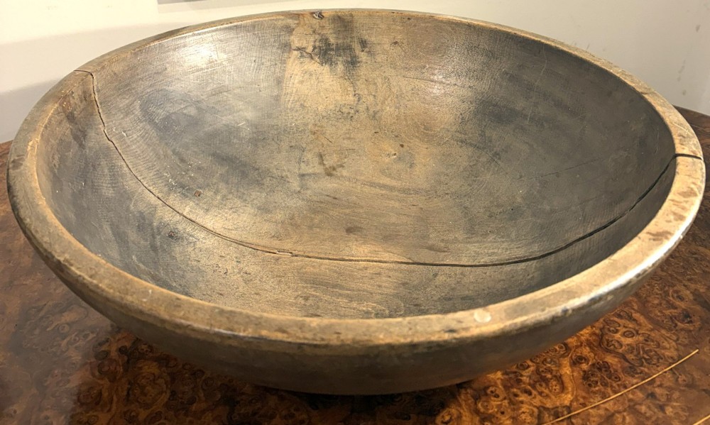 An eighteenth-century hand-turned sycamore wooden bowl displaying a weathered dark grey patina and an authentic historic timber split line. View II