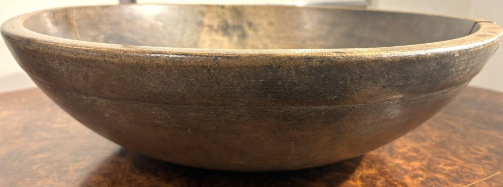 An eighteenth-century hand-turned sycamore wooden bowl displaying a weathered dark grey patina and an authentic historic timber split line. View III