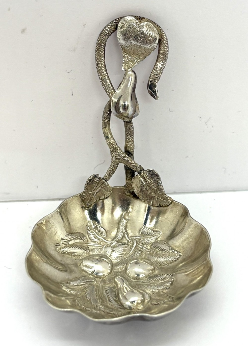 A Victorian silver caddy spoon featuring a scalloped bowl embossed with fruit and leaves alongside a branch-form handle. View II