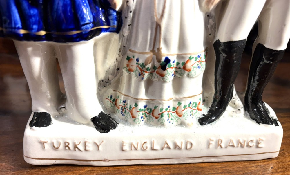 A Victorian Staffordshire earthenware figure group representing Turkey, England, and France, painted in blue, white, and orange enamels. View V