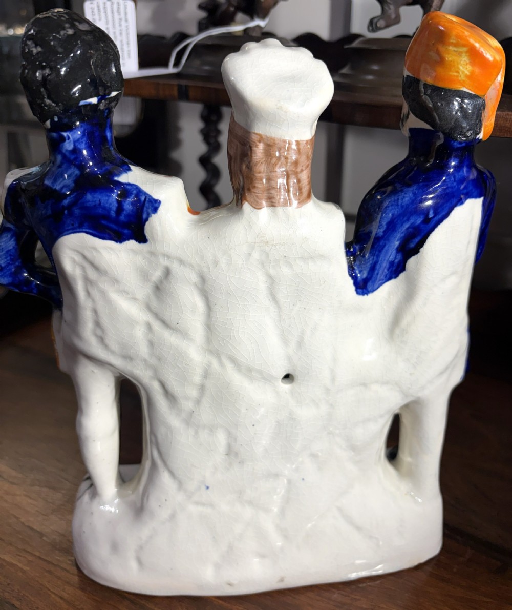 A Victorian Staffordshire earthenware figure group representing Turkey, England, and France, painted in blue, white, and orange enamels. View VI