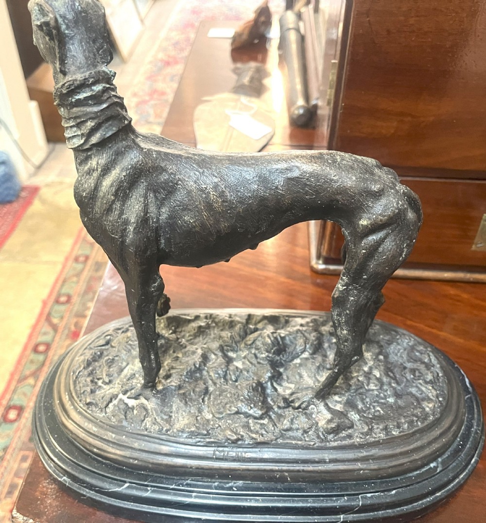 A pair of patinated dark bronze whippet dog sculptures standing on molded oval black marble bases. View IV