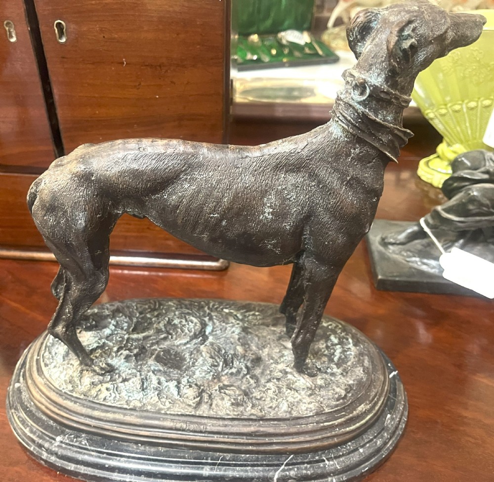 A pair of patinated dark bronze whippet dog sculptures standing on molded oval black marble bases. View VI