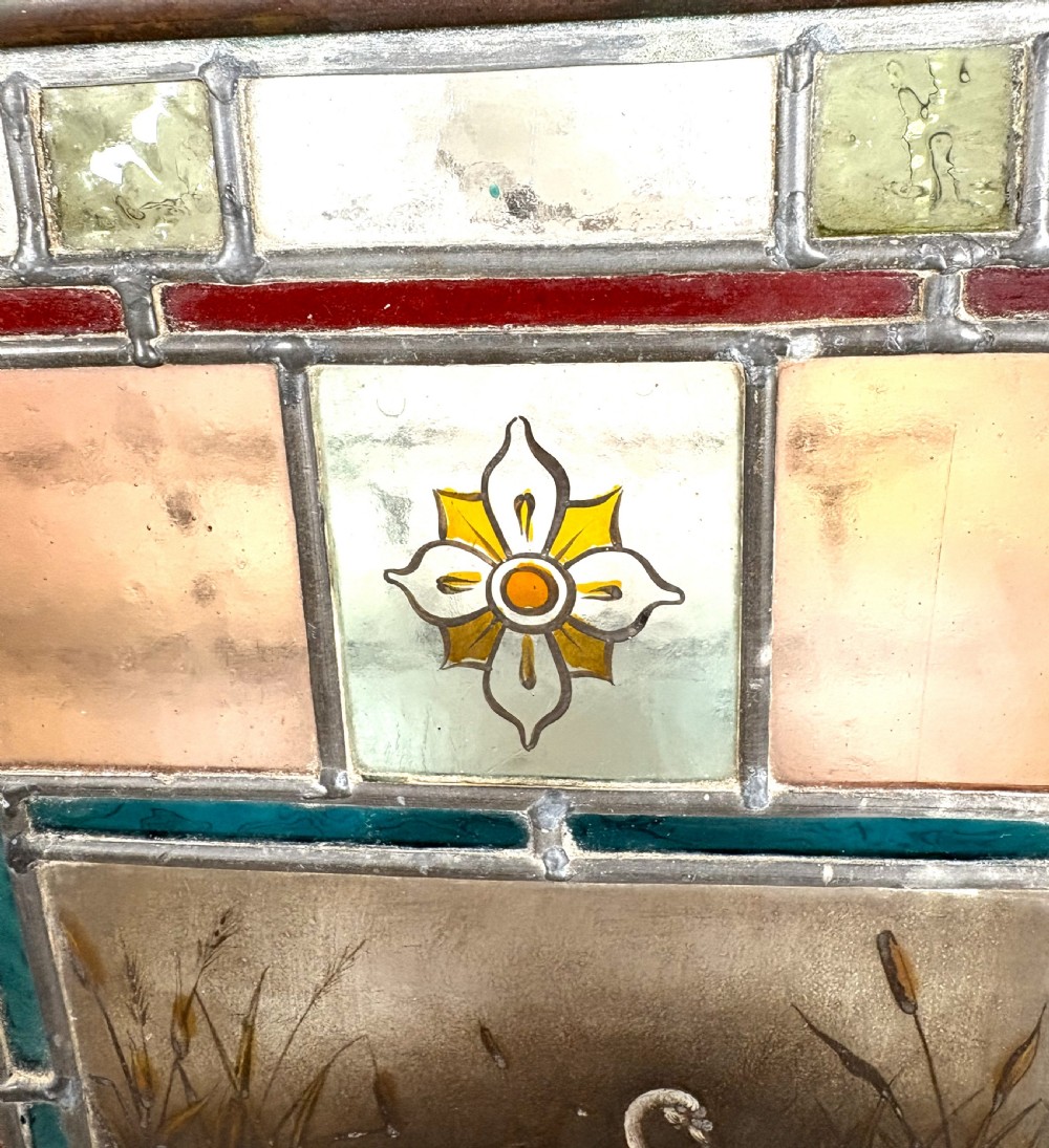 Victorian brass-framed fireguard featuring leaded stained glass panels in yellow, red, and clear geometric patterns surrounding a central hand-painted panel of a swan. View VII