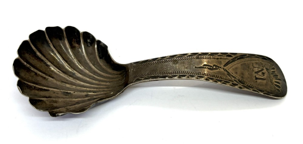 A late eighteenth-century sterling silver caddy spoon featuring a fluted shell bowl and a curved handle decorated with bright-cut engraving. View II