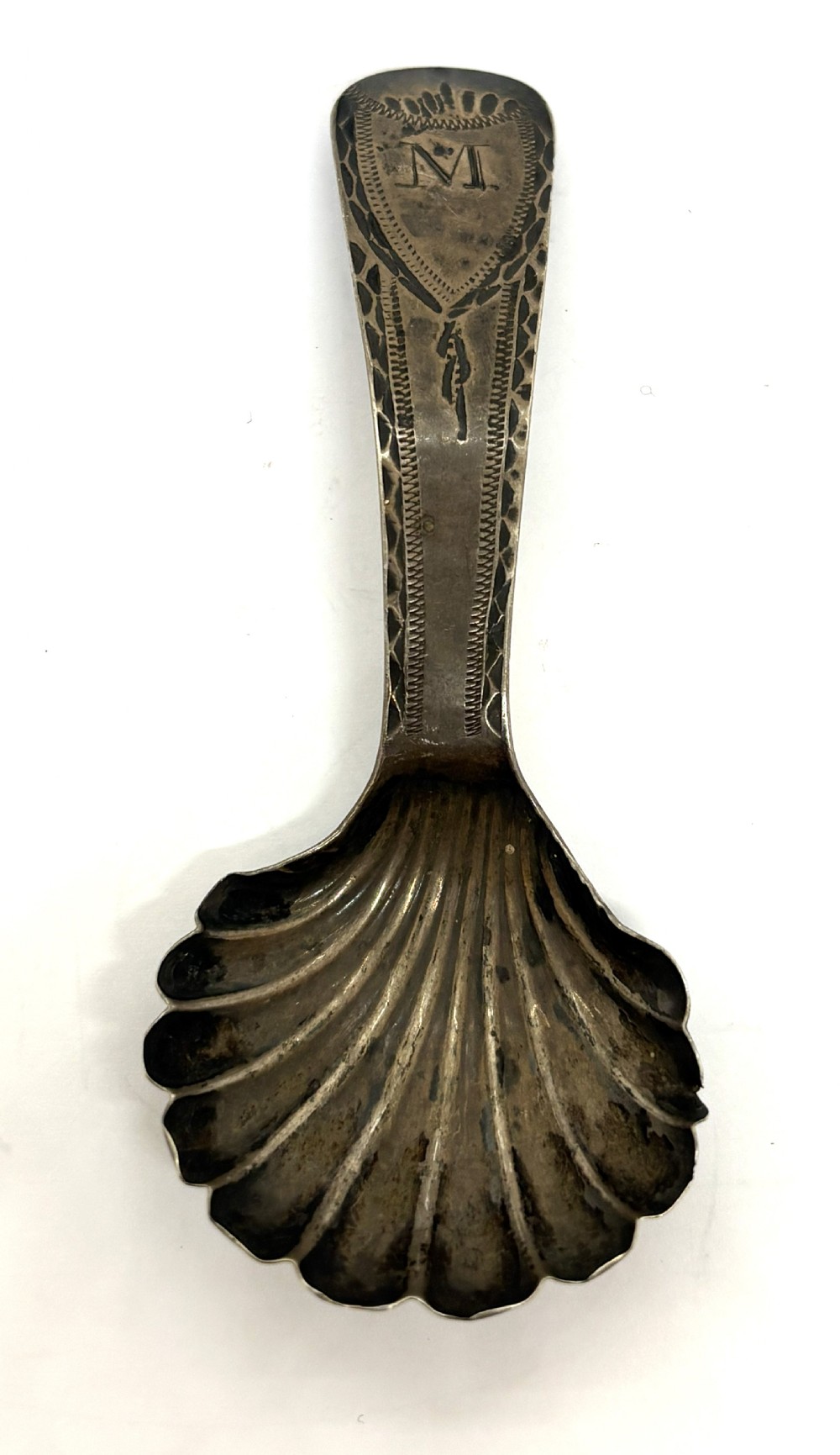 A late eighteenth-century sterling silver caddy spoon featuring a fluted shell bowl and a curved handle decorated with bright-cut engraving. View III