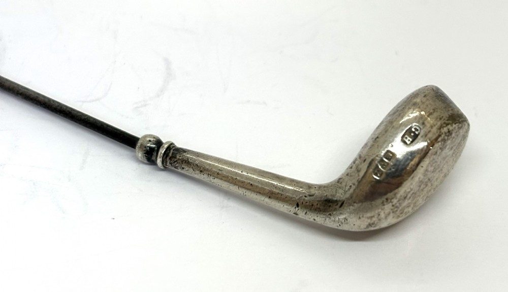 An antique silver hat pin featuring a terminal shaped as a golf club head on a long slender stem. View II