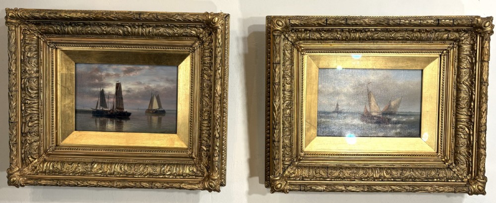 A pair of 19th-century maritime oil paintings depicting sailing ships at sea, housed in elaborate gilded ornate frames.