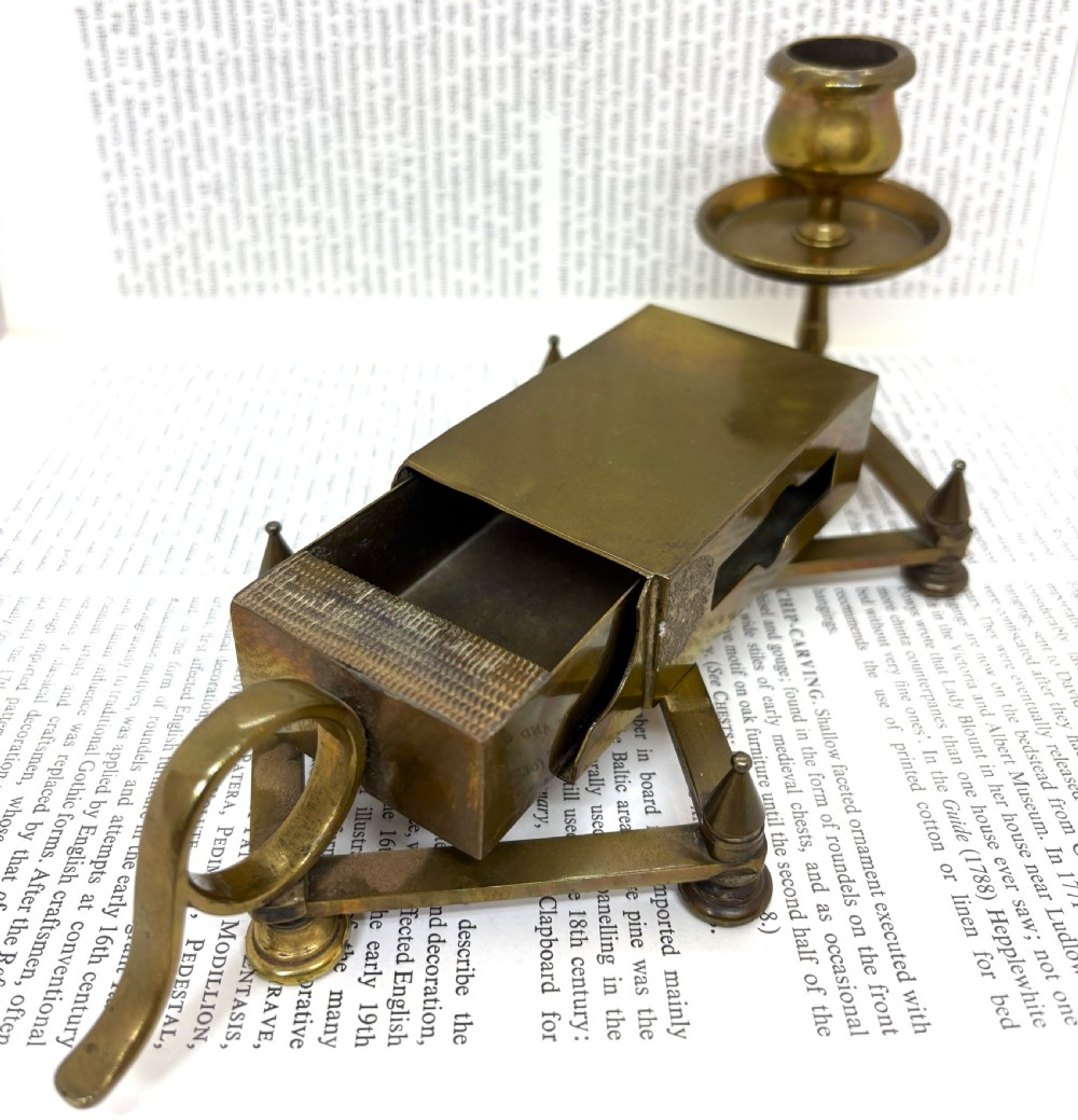 A Victorian brass chamberstick featuring an extending scissor mechanism attached to a rectangular vesta match box base. View V