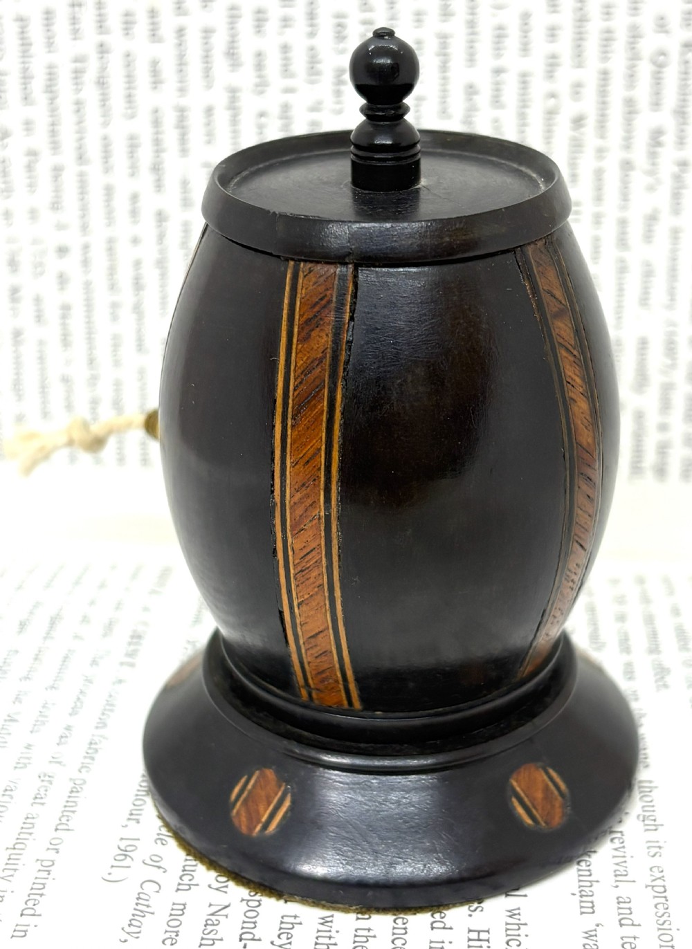 A turned dark lignum vitae wooden string barrel featuring inlaid geometric wood bands, a top turned finial, and a brass dispensing nozzle. View II