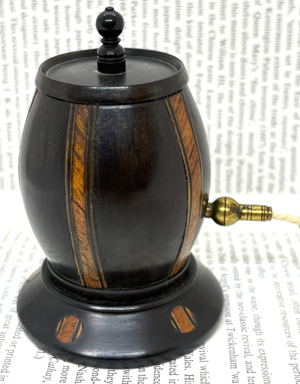 A turned dark lignum vitae wooden string barrel featuring inlaid geometric wood bands, a top turned finial, and a brass dispensing nozzle. View III